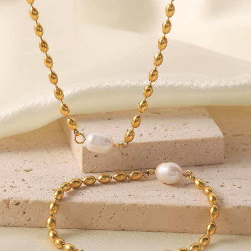 Gold necklace with pearls on a textured surface