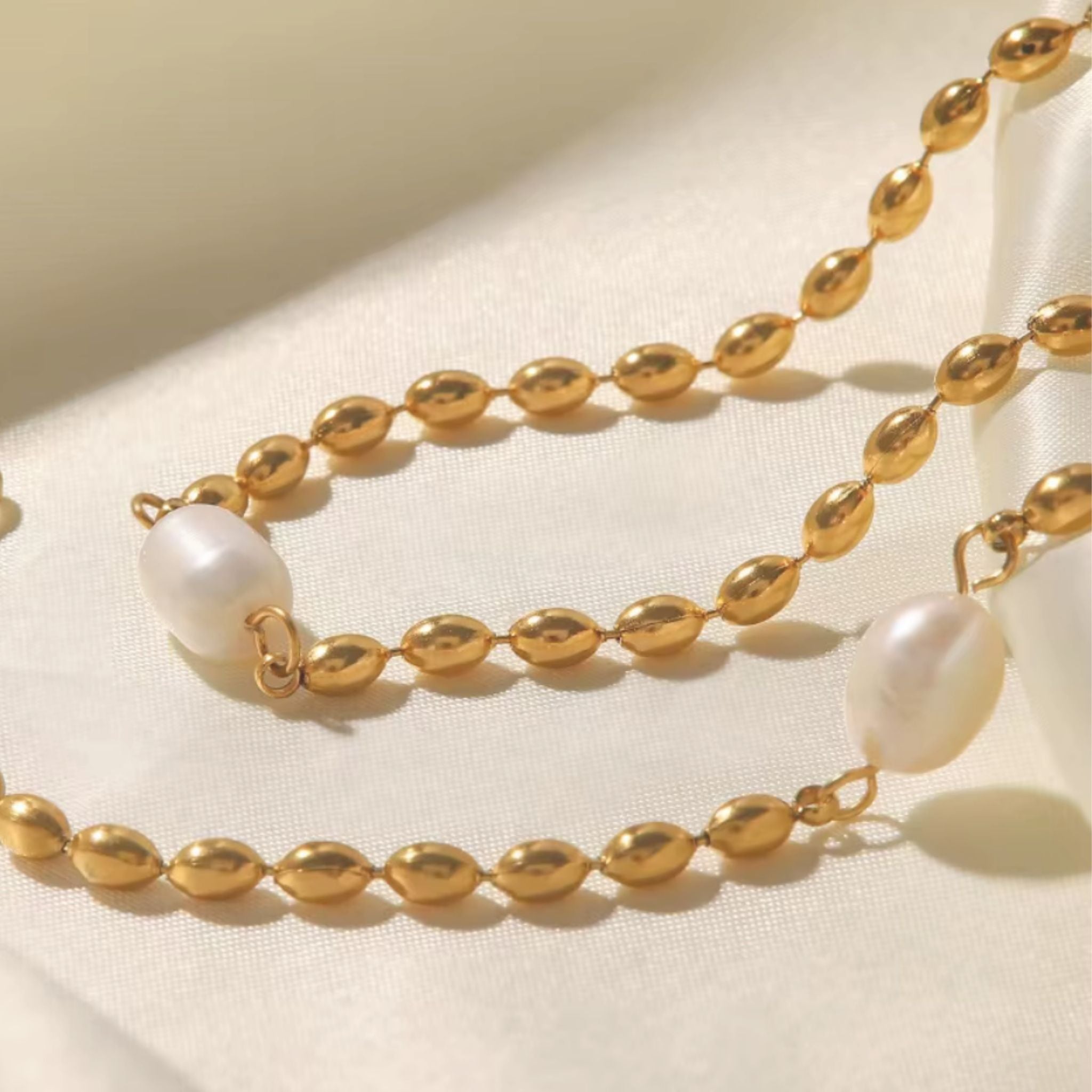 Gold necklace with pearl beads on a beige background