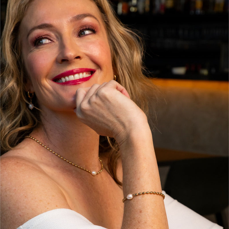 Woman with red lipstick and pearl jewelry in a bar setting