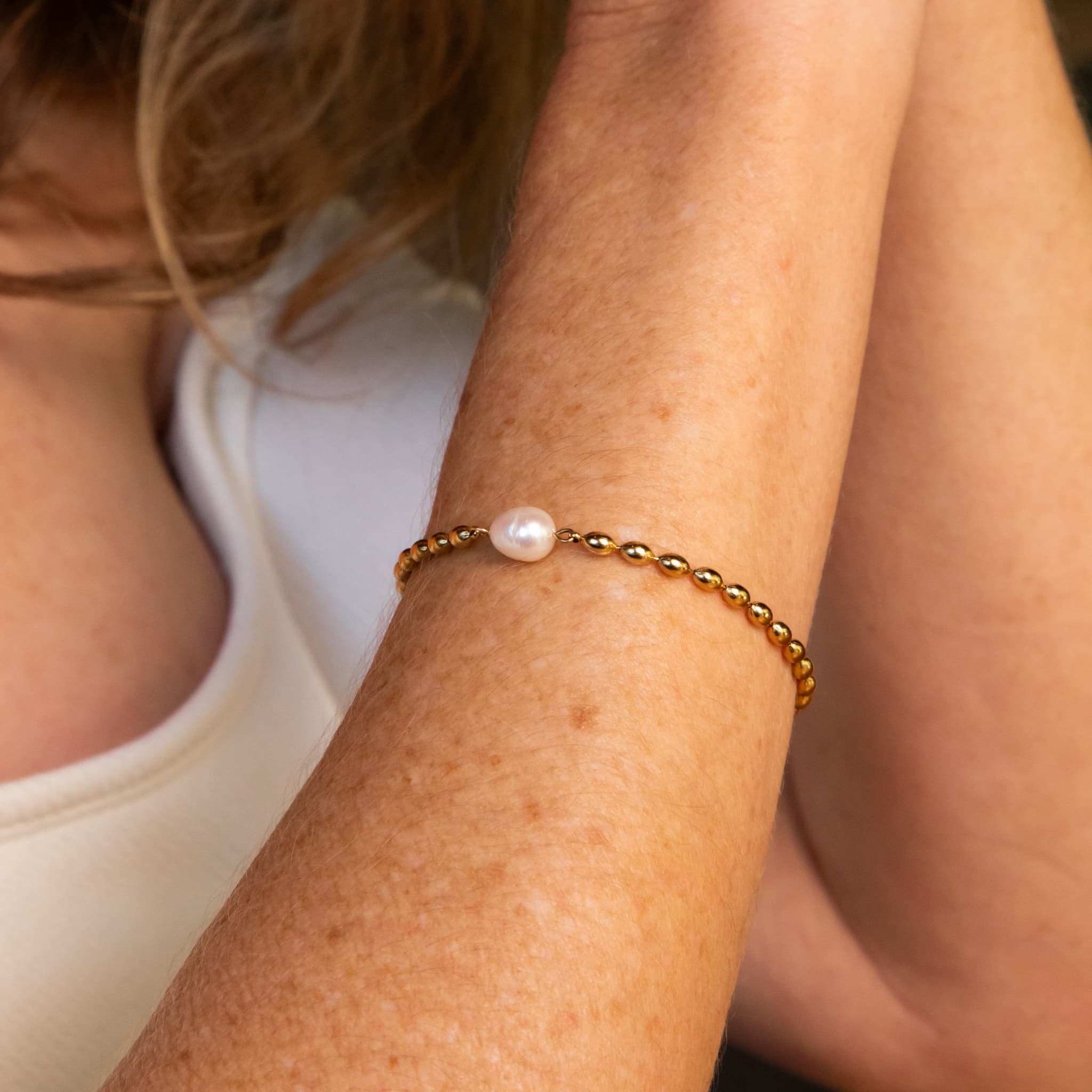 Woman wearing The Lumen single pearl on chain bracelet by Avean Jewellery